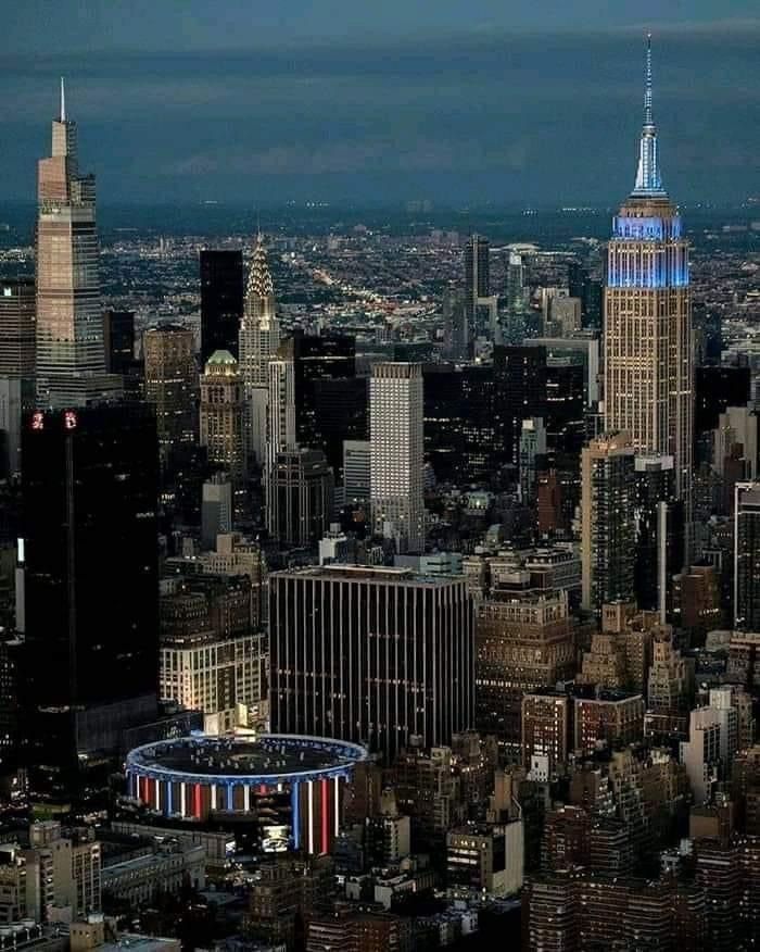 an aerial view of new york city with the empire building lit up in red, white and blue