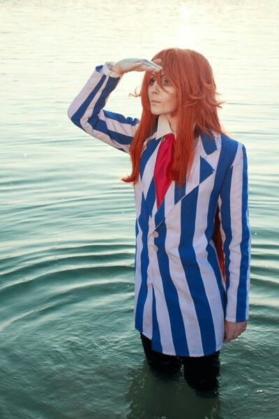 a woman with red hair wearing a blue and white striped shirt is standing in the water