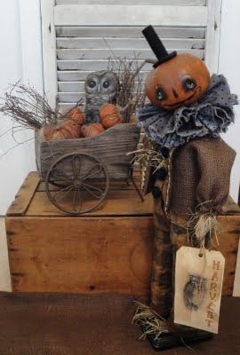 two scarecrows sitting on top of a wooden crate with pumpkins in it