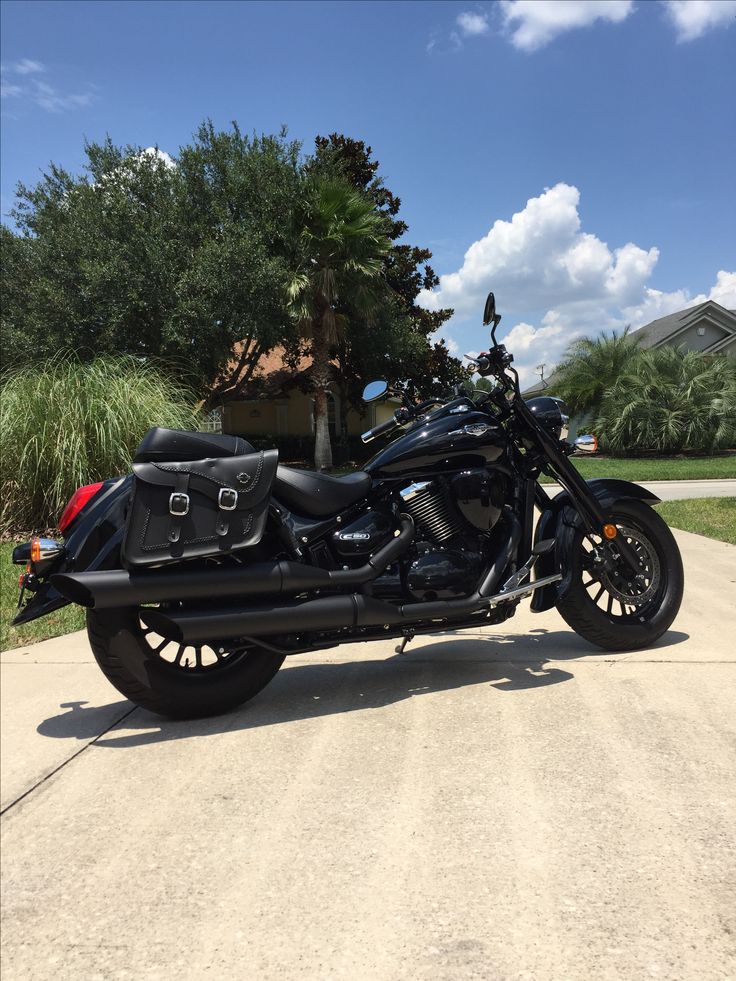 a black motorcycle parked on the side of a road next to a house and trees