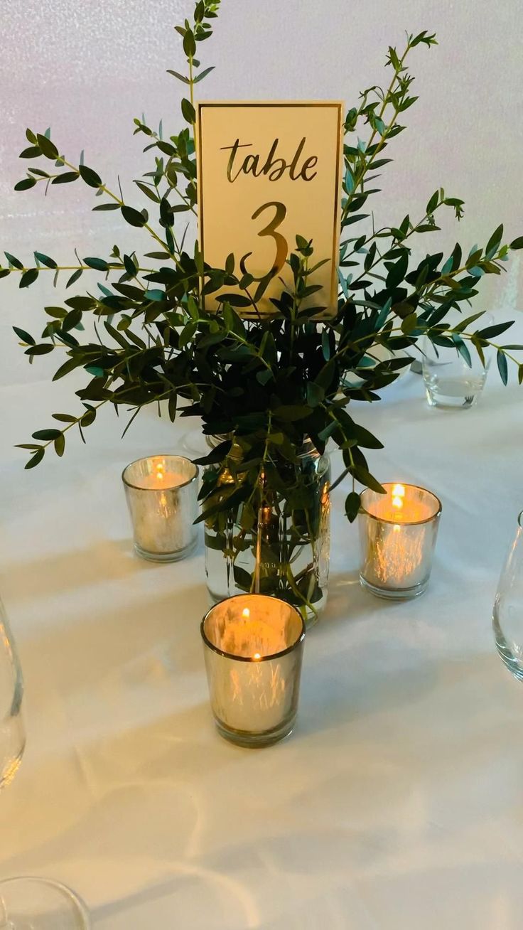 the table is set with candles and greenery in glass vases, which are labeled table 2