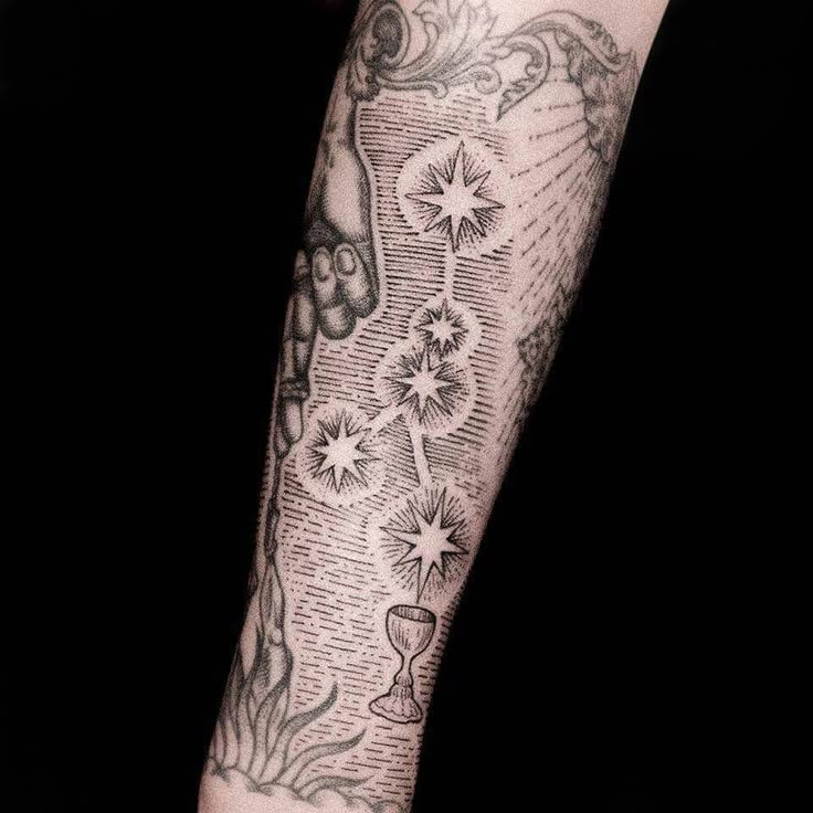 a person's arm with tattoos on it and stars in the sky above them