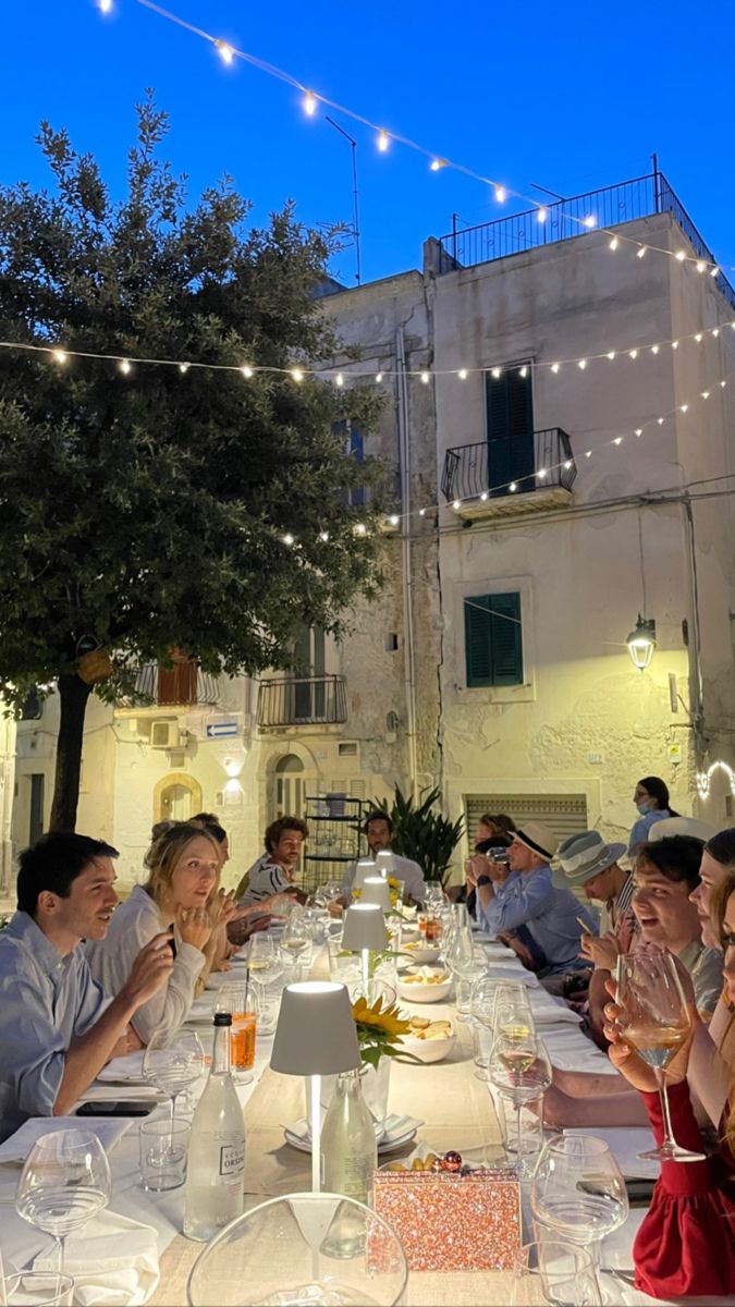 a group of people sitting at a long table with food and drinks in front of them