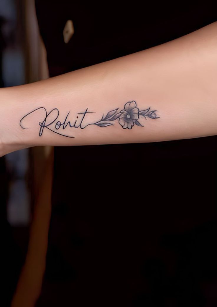 a person with a tattoo on their arm that says rohit and has flowers in it