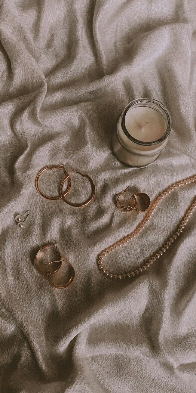 an assortment of rings and candles on a bed