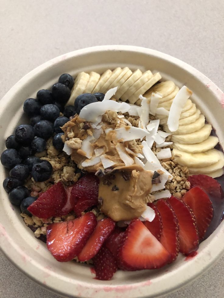 a bowl filled with granola, strawberries, bananas and blueberries in it