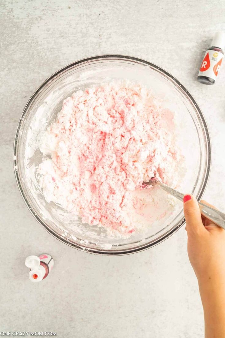 someone is mixing ingredients in a bowl with a spoon on the table next to them