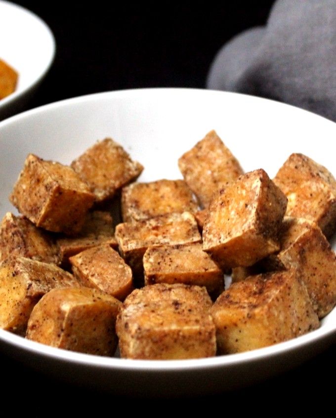 there is a white bowl filled with tofu and some sauces on the side