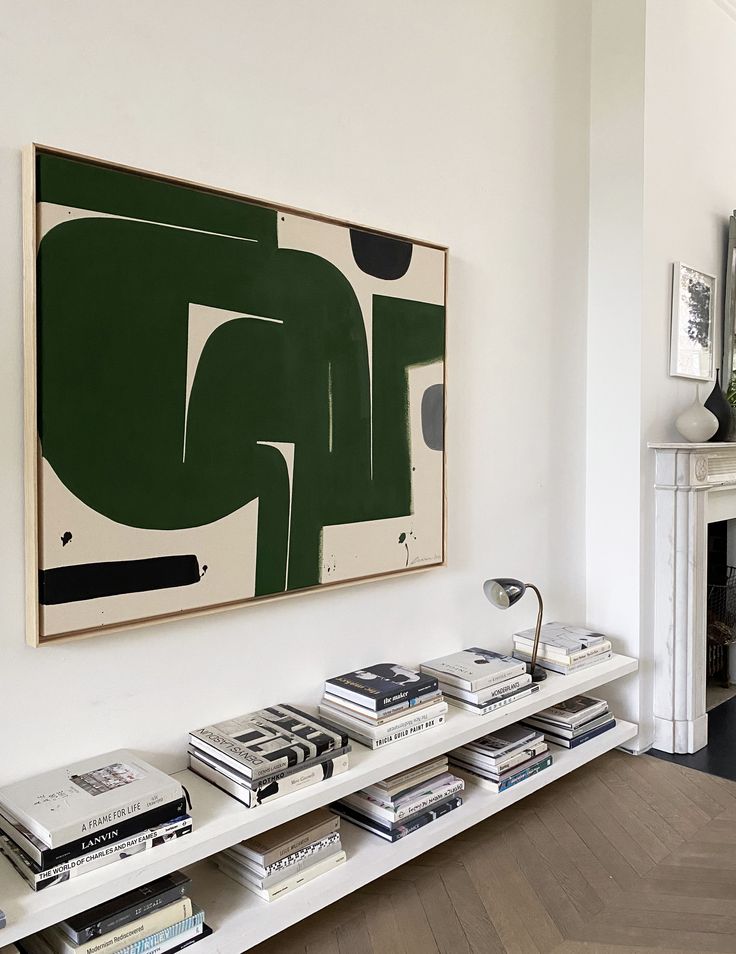 a living room filled with furniture and a large painting on the wall above bookshelves