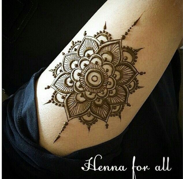 a woman's arm with a henna tattoo on the back of her shoulder