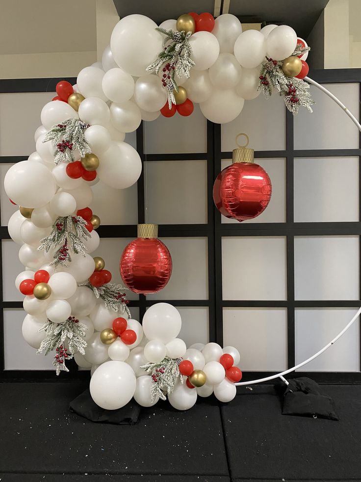 a balloon arch decorated with white, red and gold christmas decorations for the holiday season