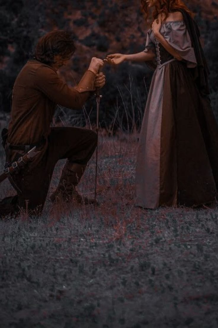 a man kneeling down next to a woman in a dress and holding her hand out