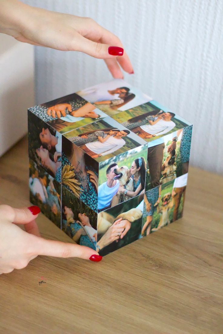 a woman's hand reaching into a box with pictures on it and another hand holding the top