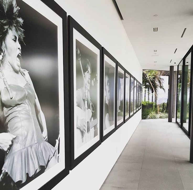 a long hallway with black and white pictures on the wall next to eachother