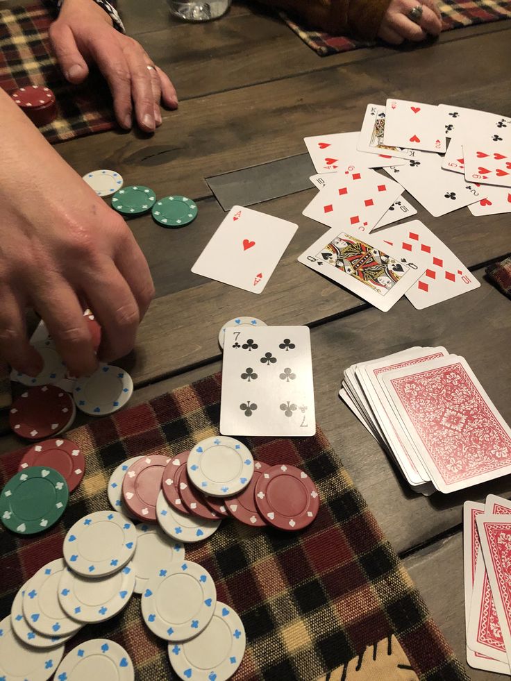 several people playing cards on a table with their hands over the top of each one