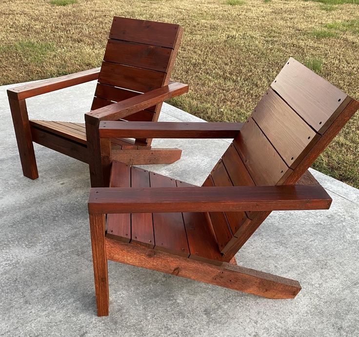 a wooden chair sitting on top of a cement slab next to a grass covered field