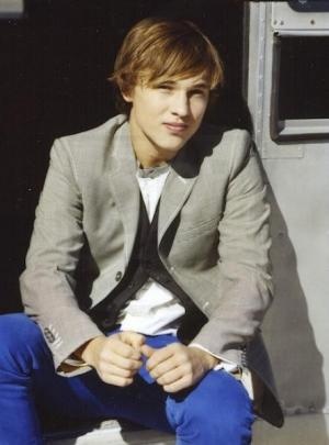 a young man in a suit and tie sitting on the ground