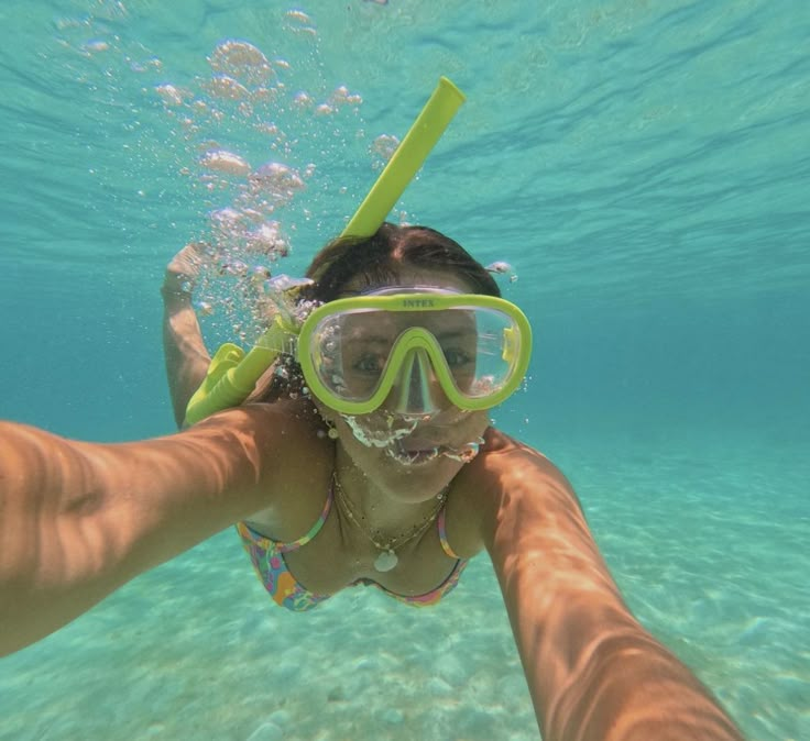 a woman wearing goggles and snorkels swimming under water