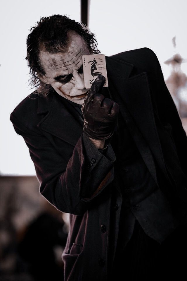 a man dressed as the joker taking a photo with his cell phone