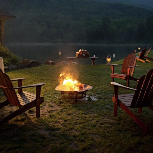 a fire pit in the middle of some lawn chairs