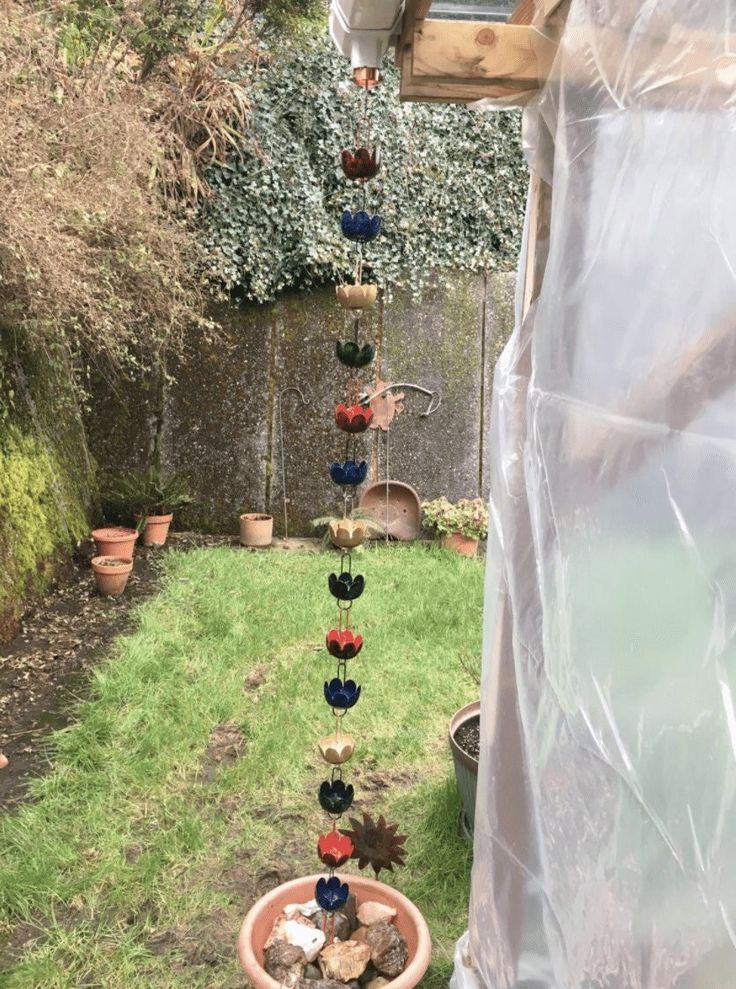 a potted plant in the middle of a yard with several small pots hanging from it's sides