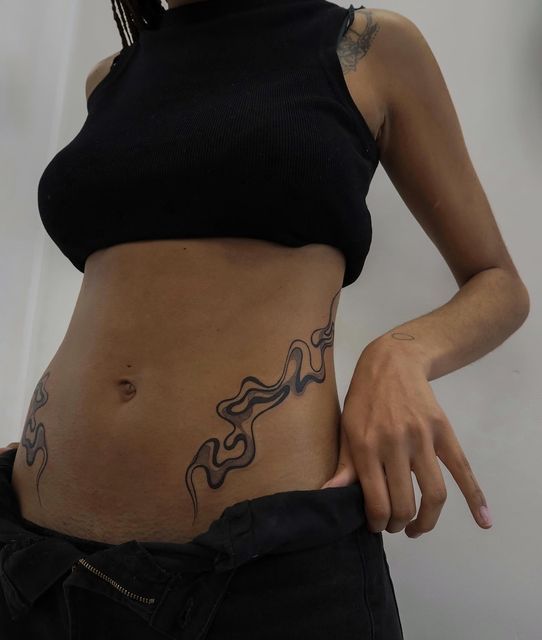 a woman is showing off her stomach tattoo