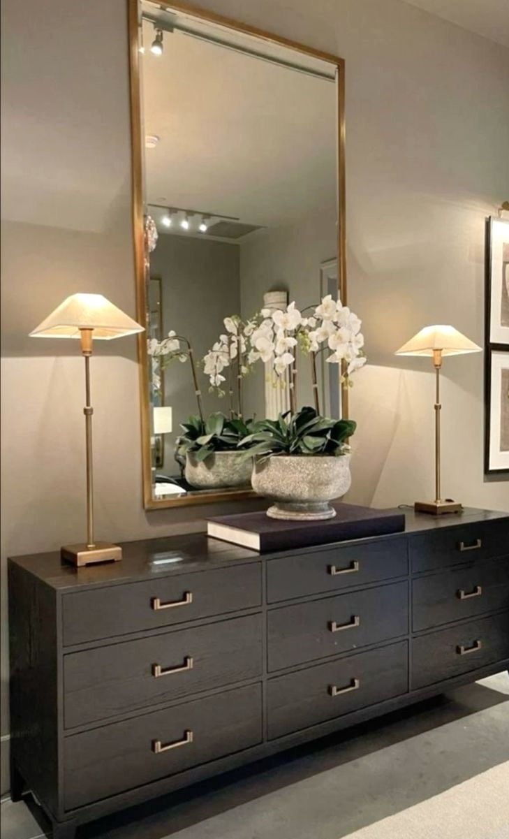 a large mirror sitting on top of a dresser next to a vase filled with flowers