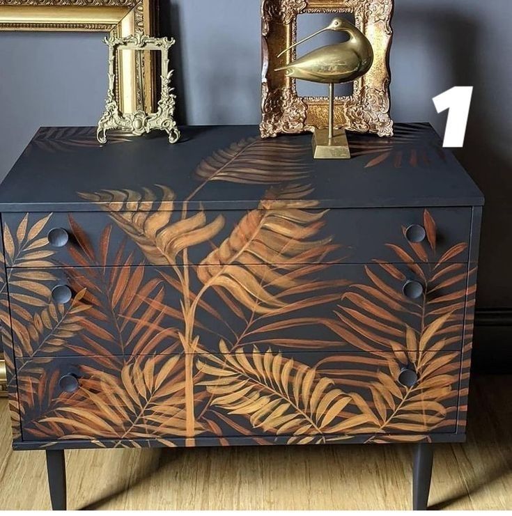 a black and gold painted chest with leaves on it