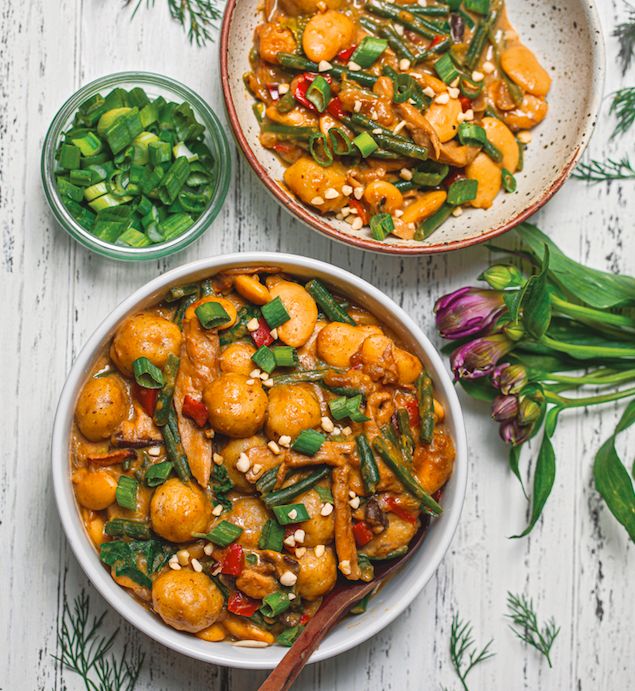 two bowls filled with food on top of a white wooden table next to green vegetables