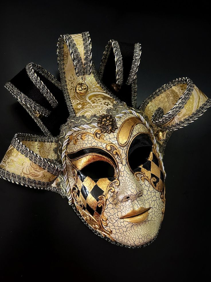 Whimsical and colorful this gold black tone Jester mask is inspired by the traditional Venetian Carnival. This mask features vibrant colors, intricate designs, and exaggerated features to convey a sense of playfulness and jest. Traditional Masks And Prosthetics For Mardi Gras Carnival, Artistic Masks And Prosthetics For Mardi Gras Carnival, Traditional Masks For Mardi Gras Carnival, Gold Fantasy Festival Masks And Prosthetics, Gold Masks And Prosthetics For Carnival Festival, Gold Masquerade Mask For Mardi Gras Festival, Mardi Gras Masks And Prosthetics, Traditional Masks And Prosthetics For Carnival, Multicolor Masks And Prosthetics For Carnival Masquerade