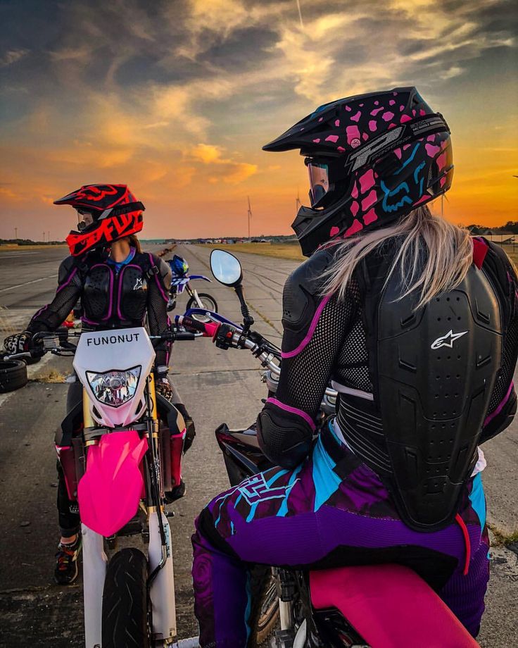 two motorcyclists are sitting on their bikes at sunset