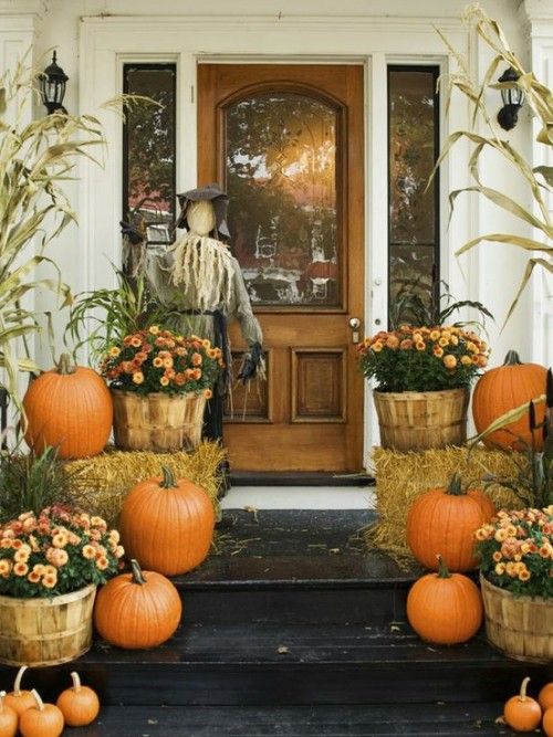 pumpkins and hay bales in front of a door with scarecrow on it