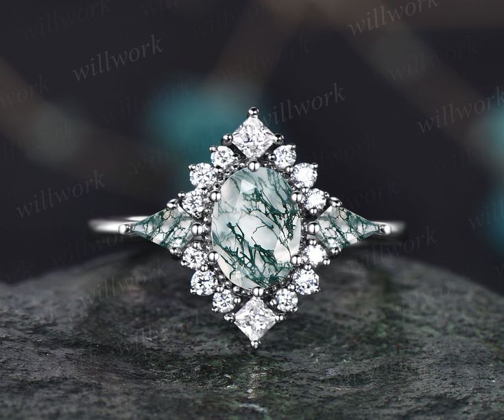 a diamond ring sitting on top of a rock with white diamonds in the center and an emerald