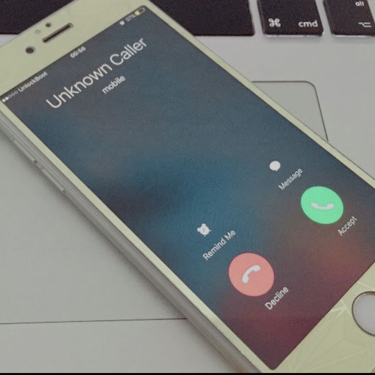 an iphone sitting on top of a laptop computer next to a phone with the unknown caller app