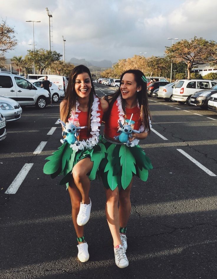 two young women dressed in green and white hula skirts are smiling at the camera