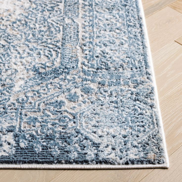 a blue and white area rug on a wooden floor with a light colored wood floor