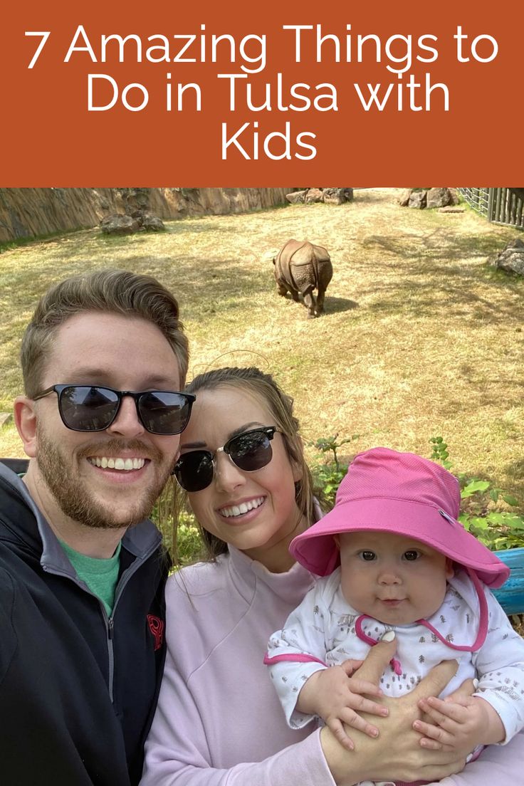 a man and woman holding a baby with rhinos in the background text reads 7 amazing things to do in tusa with kids