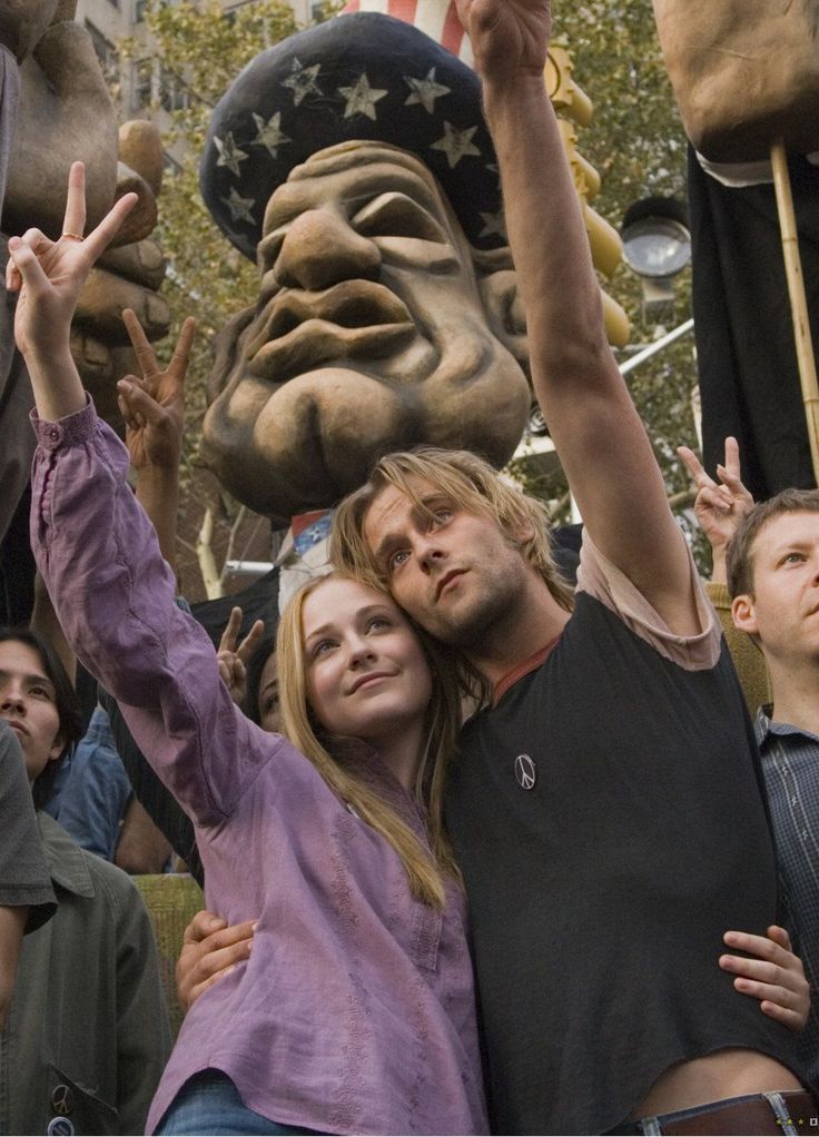 a group of people standing next to each other in front of a large statue with a face on it