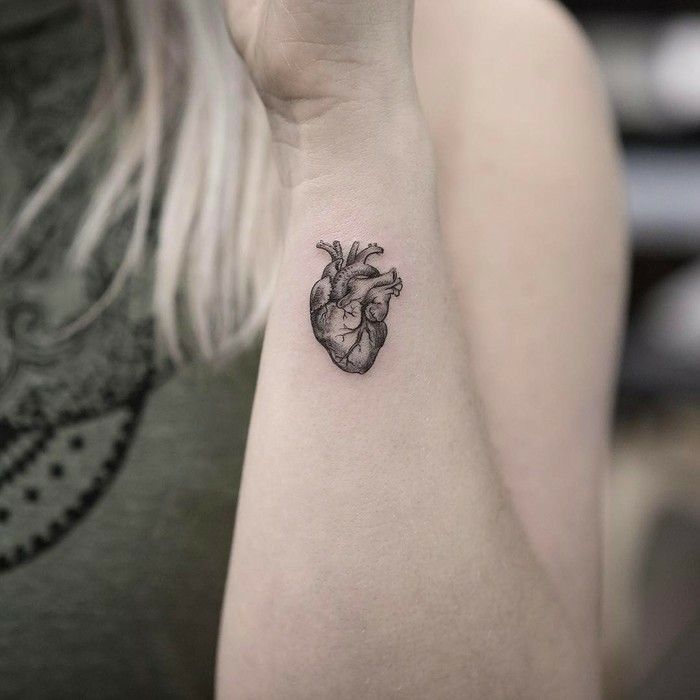 a small heart tattoo on the left arm