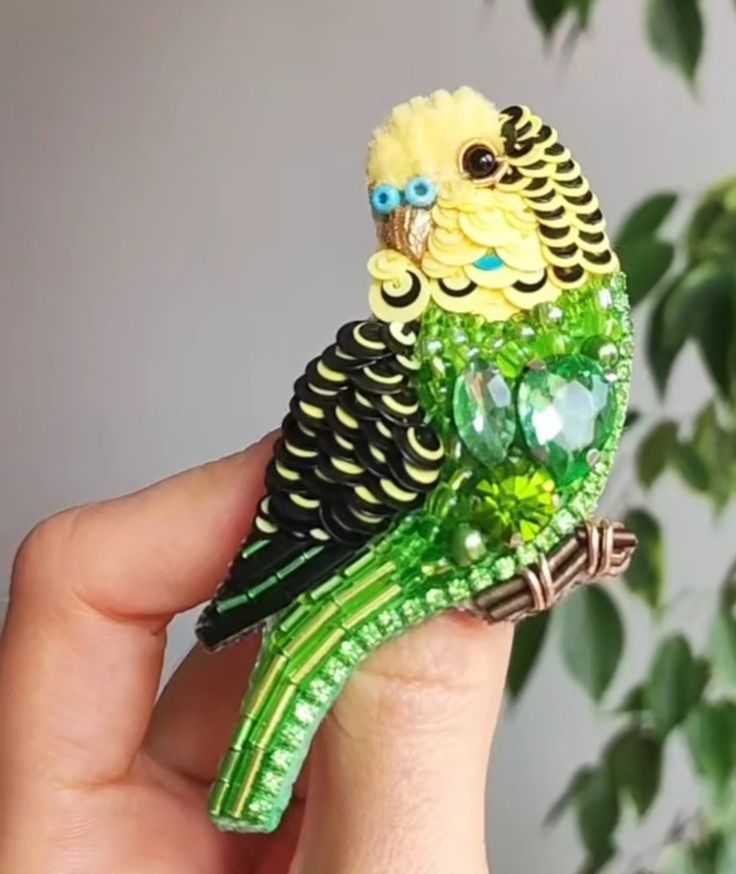 a small green and yellow bird sitting on top of a finger