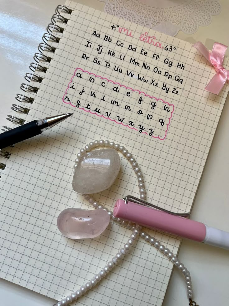 a notepad with writing on it next to a pen and some other items that include beads