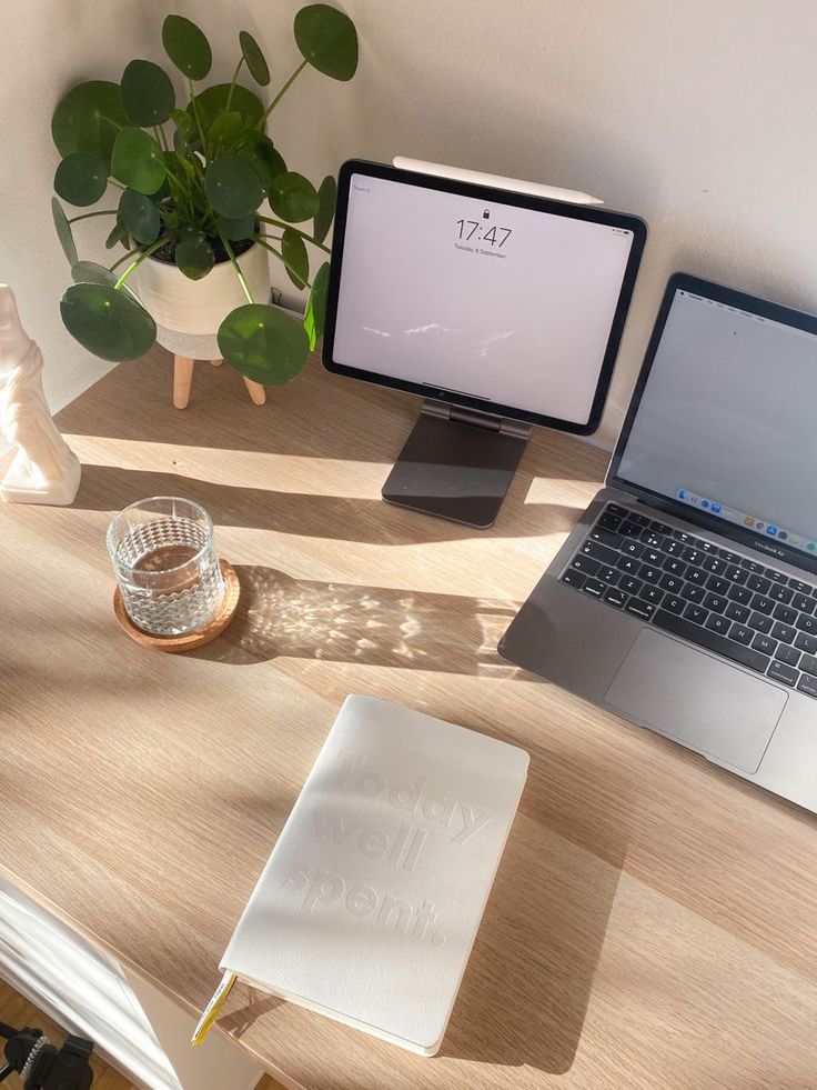 an open laptop computer sitting on top of a wooden desk next to a desktop computer