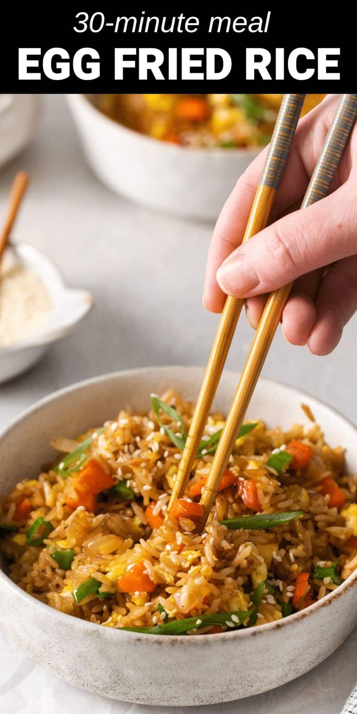 someone holding chopsticks over a bowl of egg fried rice