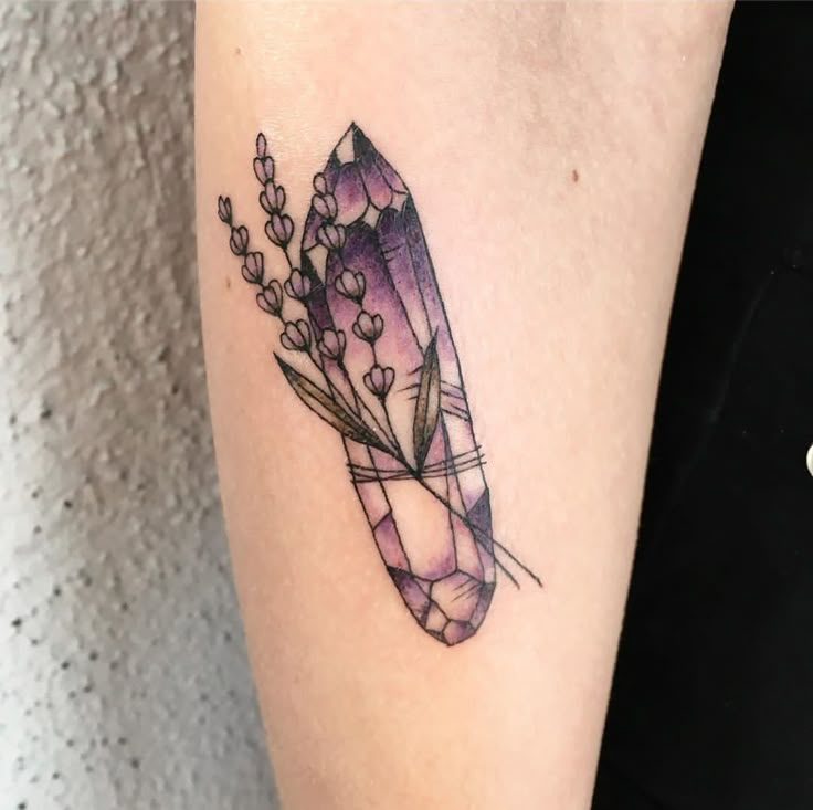 a woman's arm with a tattoo on it that has an arrow and flowers