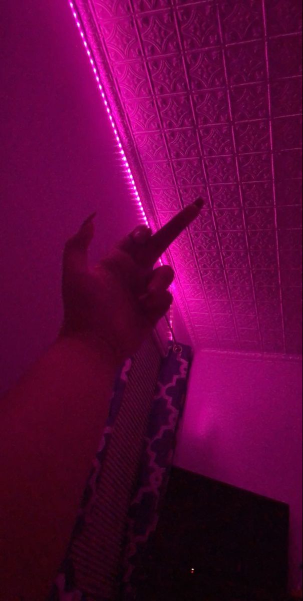 a person pointing to the ceiling with purple light