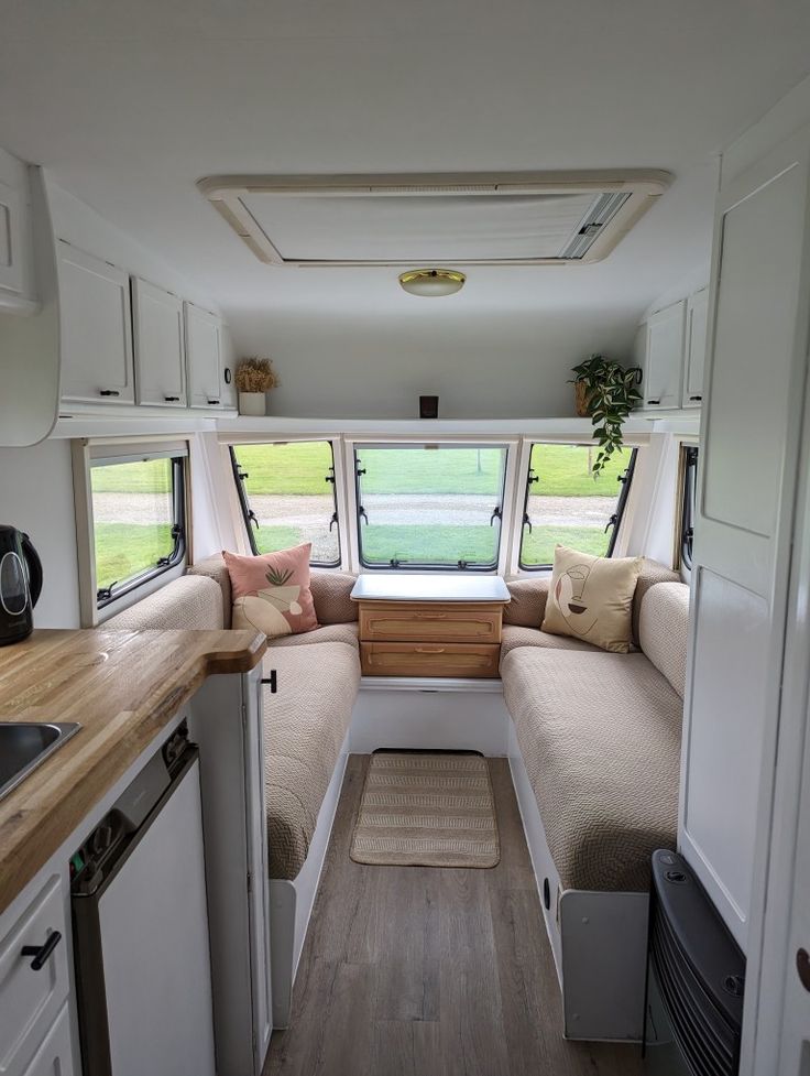 the interior of a small camper with wood flooring and white cabinets is shown