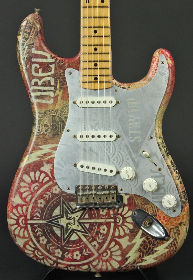 an electric guitar that has been painted with designs on it and is sitting on a stand