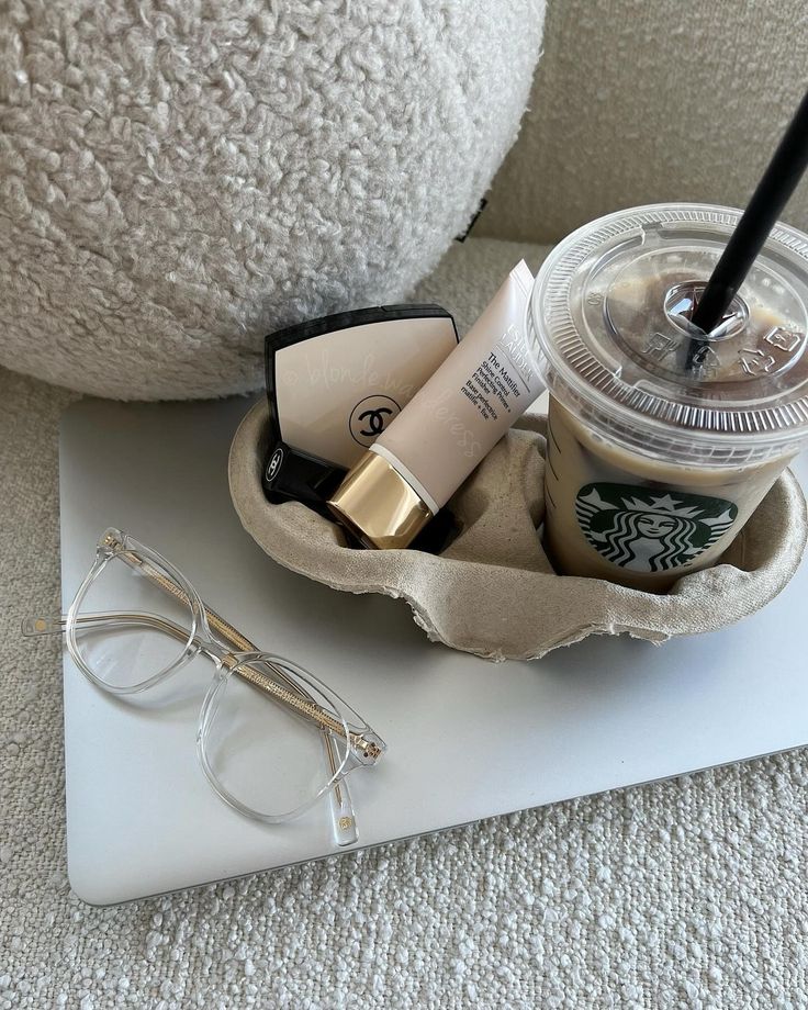 a starbucks drink and some glasses are on a tray next to a pair of eyeglasses