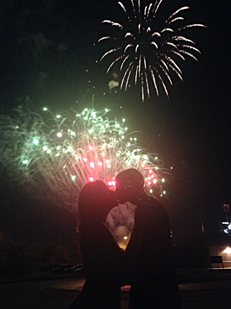 two people are kissing in front of fireworks