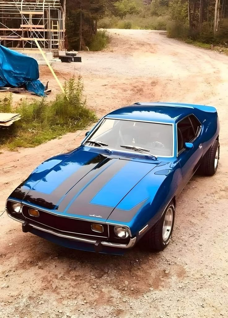 a blue muscle car parked on the side of a dirt road